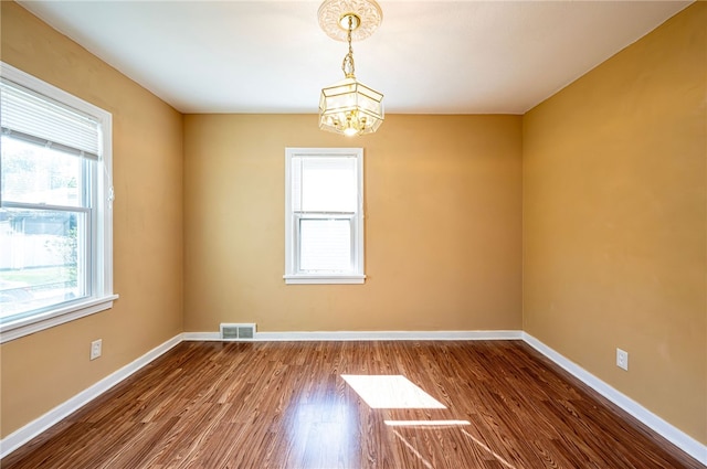 empty room with a notable chandelier and hardwood / wood-style flooring