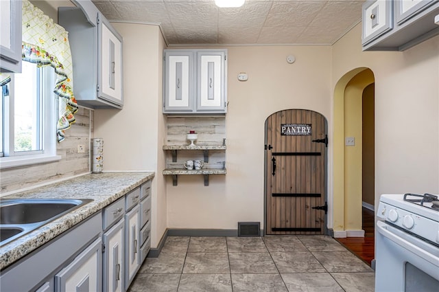 kitchen with decorative backsplash, white cabinets, a textured ceiling, and white range oven