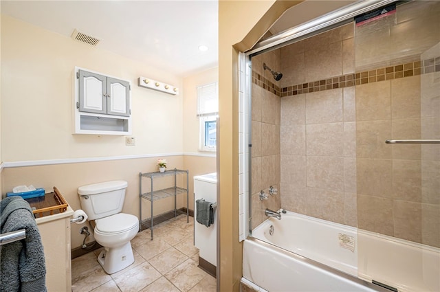 bathroom with toilet, tiled shower / bath combo, and tile patterned flooring