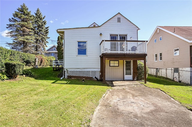 back of property featuring a wooden deck and a lawn