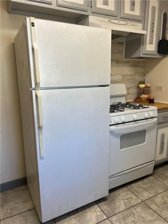 kitchen featuring decorative backsplash, white appliances, and light tile patterned floors