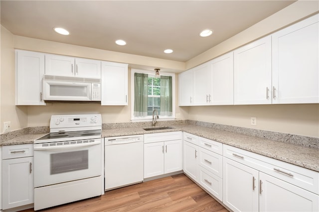 kitchen with light stone countertops, sink, light hardwood / wood-style floors, white appliances, and white cabinets