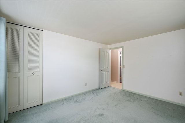 unfurnished bedroom with light carpet and a closet