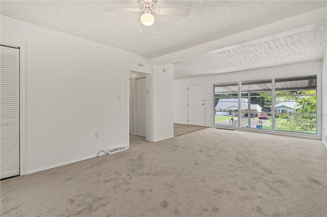 carpeted spare room featuring ceiling fan and a textured ceiling