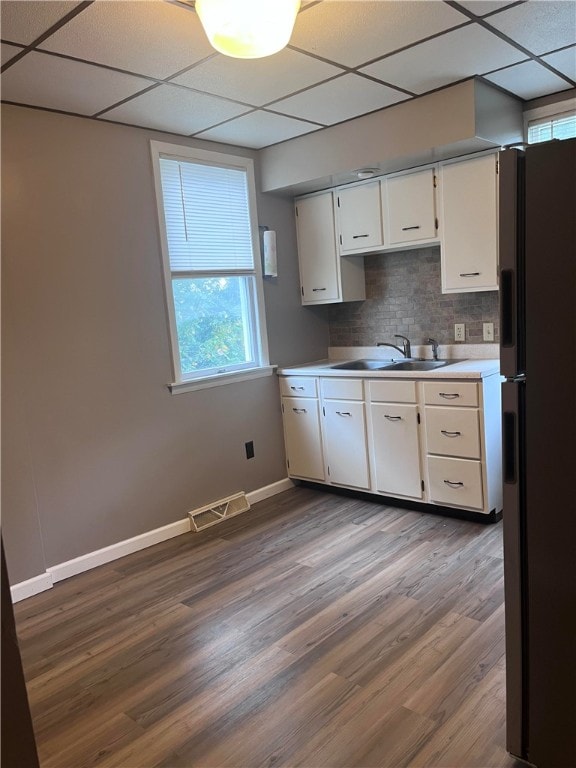 kitchen featuring wood-type flooring, refrigerator, a paneled ceiling, backsplash, and white cabinets