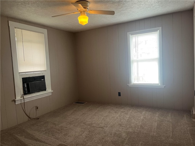 carpeted empty room featuring cooling unit, ceiling fan, a fireplace, and a textured ceiling