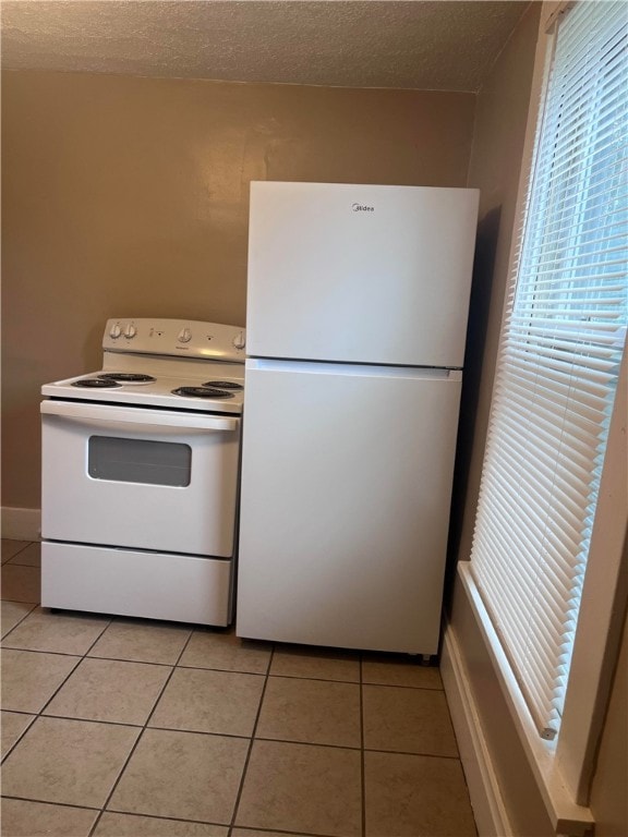 kitchen featuring light tile patterned flooring, white appliances, and a textured ceiling