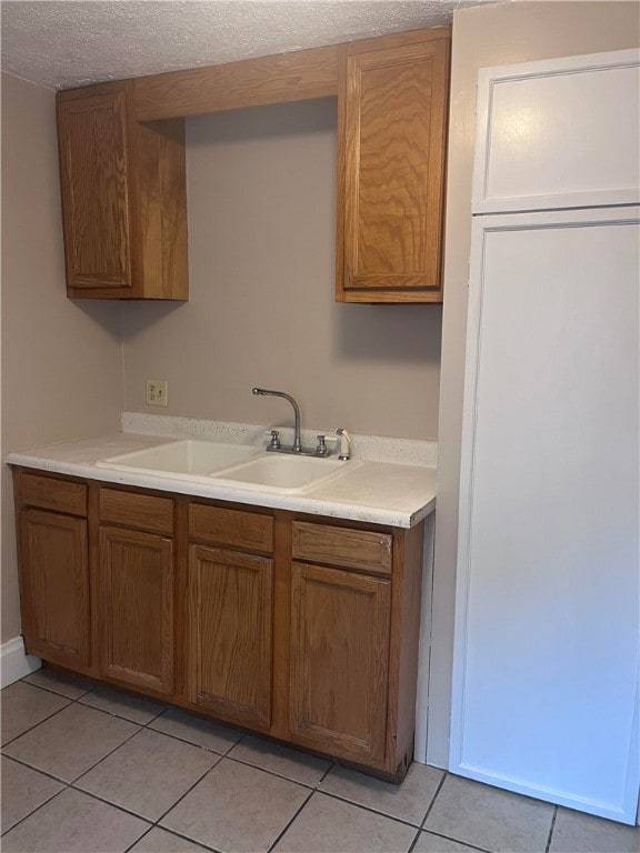 kitchen with sink, light tile patterned floors, and a textured ceiling