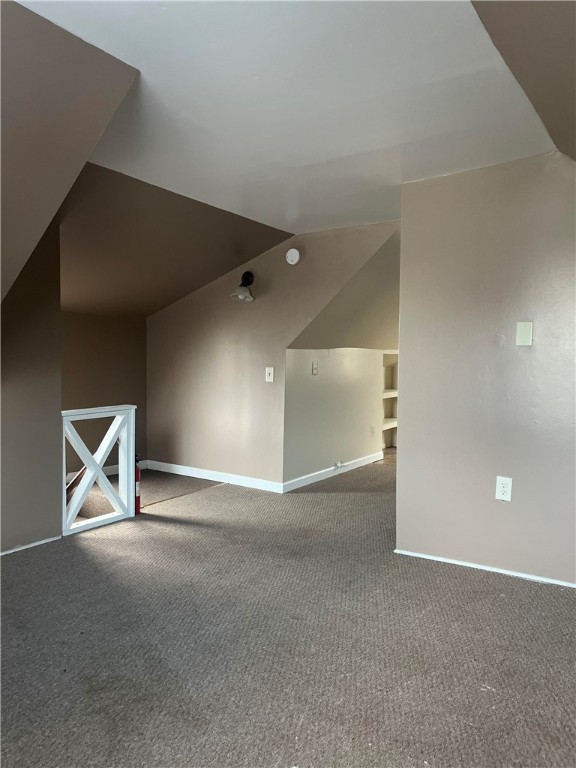 bonus room with carpet flooring and vaulted ceiling