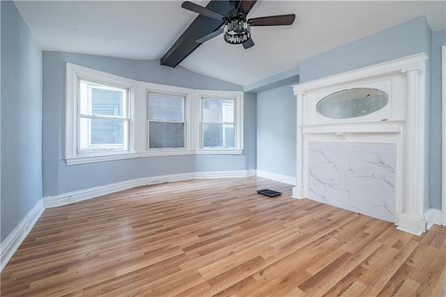 unfurnished living room featuring ceiling fan, light hardwood / wood-style flooring, lofted ceiling with beams, and a wealth of natural light