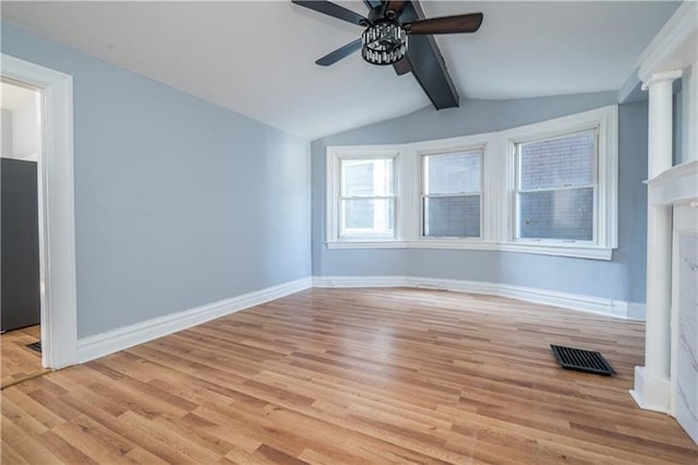 spare room with a fireplace, light hardwood / wood-style floors, lofted ceiling with beams, and ceiling fan