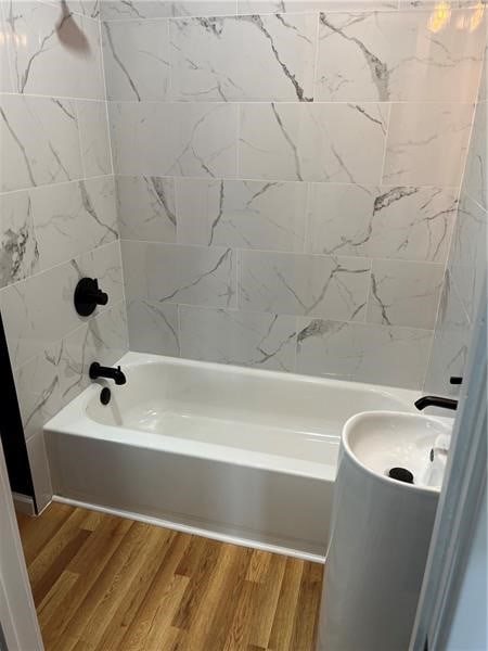 bathroom featuring wood-type flooring and tiled shower / bath