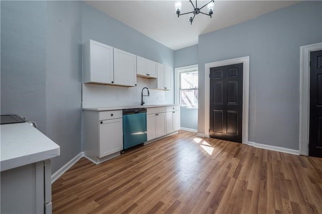 kitchen with white cabinets, sink, stainless steel dishwasher, a chandelier, and hardwood / wood-style flooring