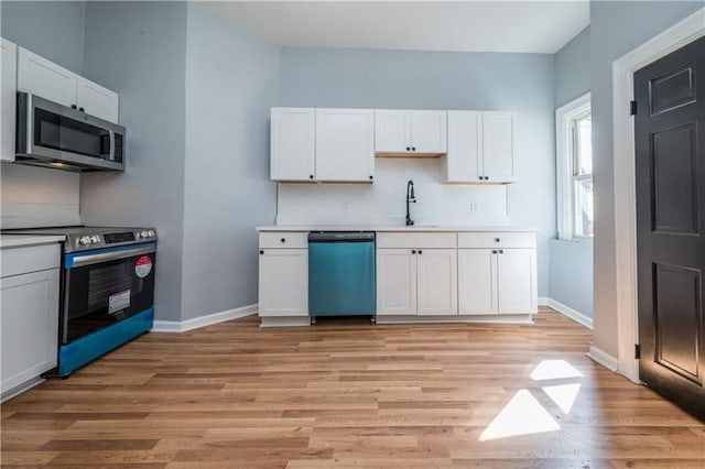 kitchen featuring appliances with stainless steel finishes, light hardwood / wood-style floors, and white cabinetry