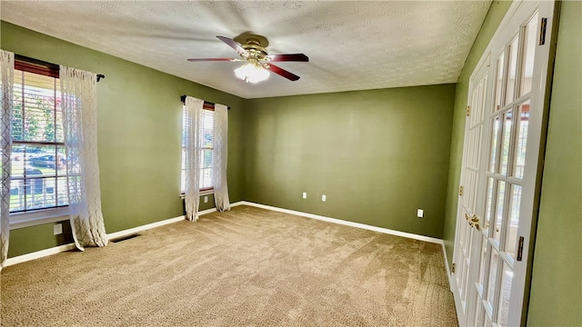 carpeted spare room with ceiling fan, a textured ceiling, and plenty of natural light