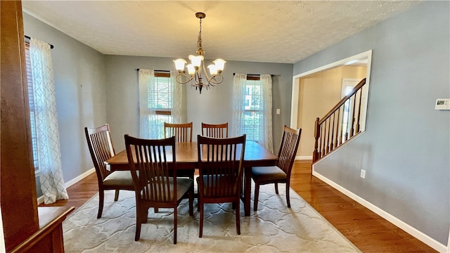 dining area featuring hardwood / wood-style floors, a notable chandelier, and a textured ceiling