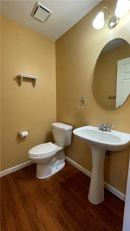 bathroom featuring hardwood / wood-style floors, toilet, and a textured ceiling