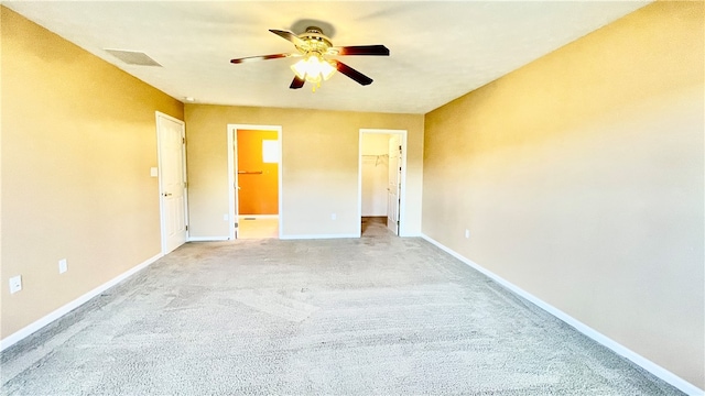 unfurnished bedroom with light carpet, a spacious closet, ceiling fan, and a closet