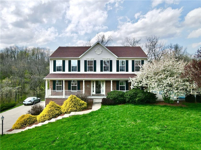 colonial home featuring a front yard and covered porch