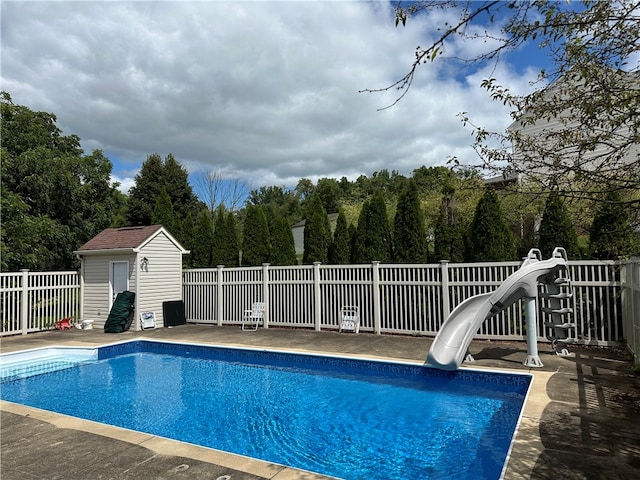 view of pool featuring a water slide, a patio area, and an outdoor structure