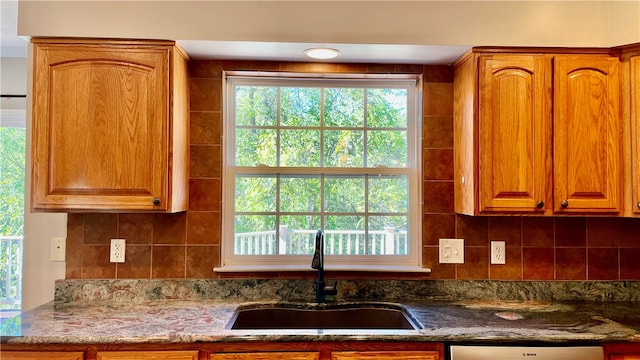 kitchen featuring dark stone countertops, dishwasher, sink, and tasteful backsplash