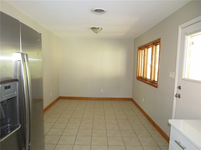 kitchen featuring light tile patterned flooring, stainless steel refrigerator with ice dispenser, and white cabinetry