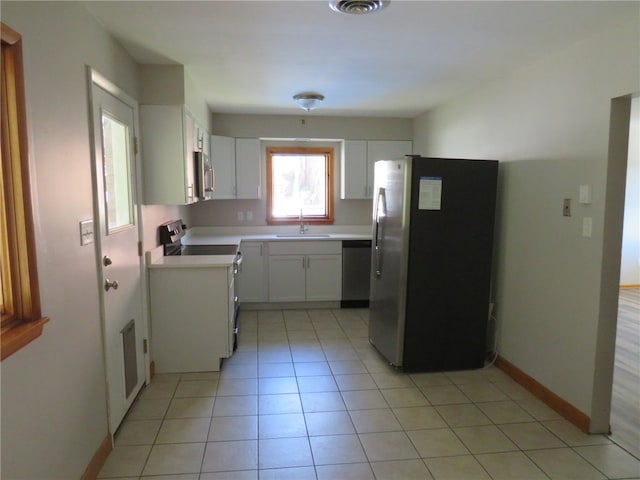 kitchen featuring stainless steel appliances, light tile patterned flooring, white cabinets, and sink