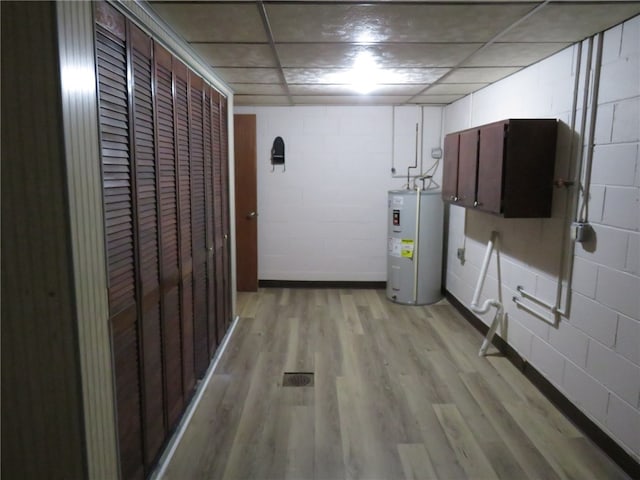 clothes washing area featuring cabinets, light hardwood / wood-style floors, and electric water heater