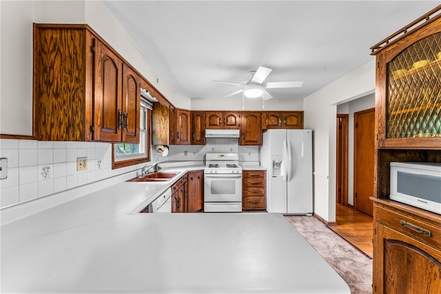 kitchen featuring ceiling fan, decorative backsplash, white appliances, sink, and light hardwood / wood-style floors