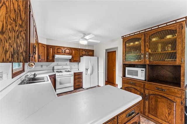 kitchen featuring white appliances, backsplash, sink, and ceiling fan