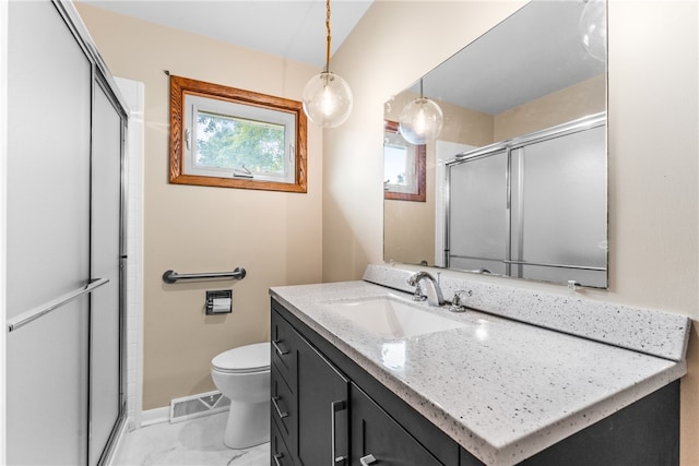 bathroom featuring vanity, a shower with shower door, and toilet