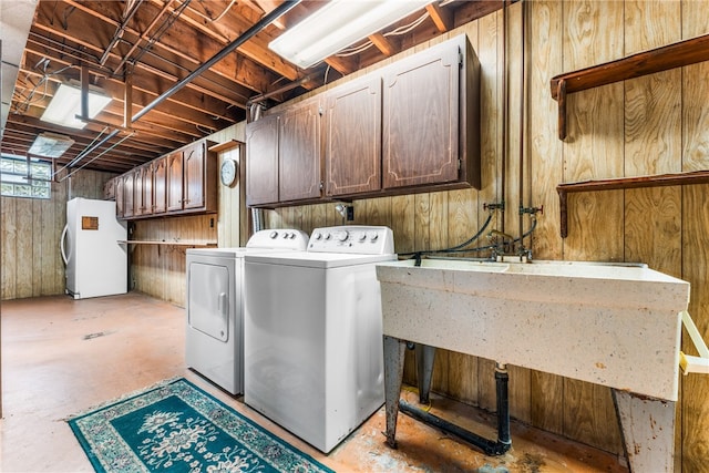 washroom with wood walls, separate washer and dryer, and cabinets