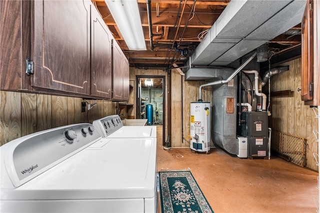 clothes washing area featuring wood walls, heating unit, washer and dryer, and water heater