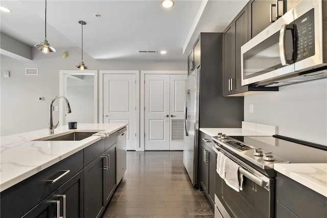 kitchen featuring light stone counters, sink, decorative light fixtures, stainless steel appliances, and dark hardwood / wood-style flooring