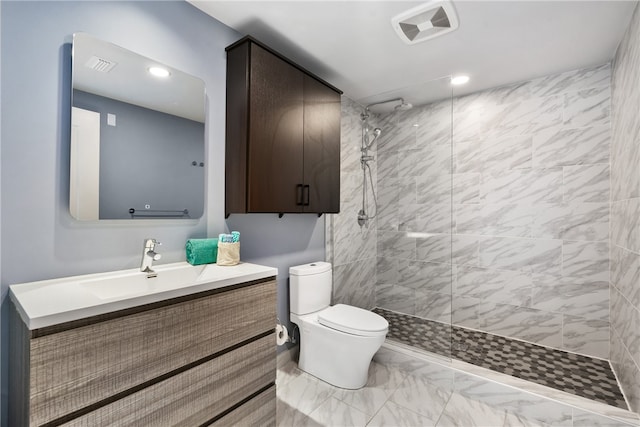 bathroom with tiled shower, vanity, and toilet