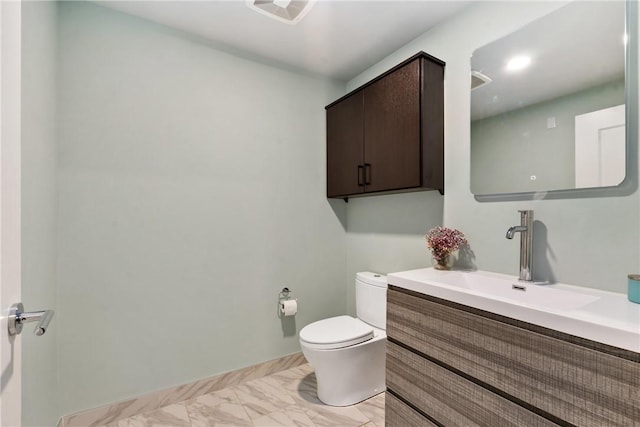 half bath with toilet, marble finish floor, baseboards, and vanity