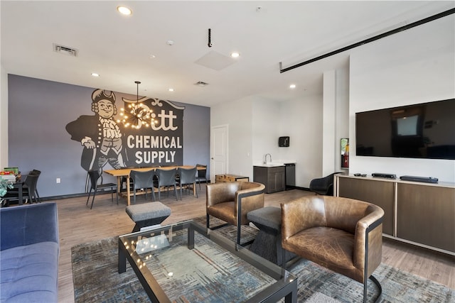 living room with hardwood / wood-style flooring, sink, and a notable chandelier