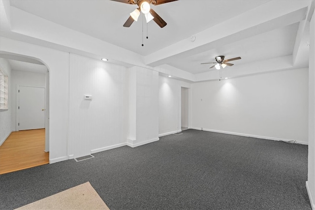 carpeted empty room with a raised ceiling and ceiling fan