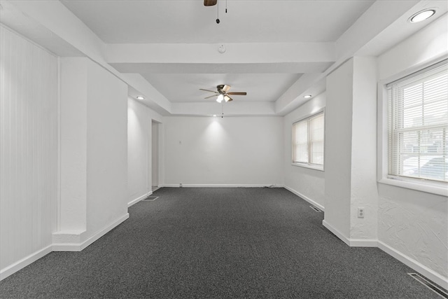 spare room featuring ceiling fan, a tray ceiling, and dark colored carpet