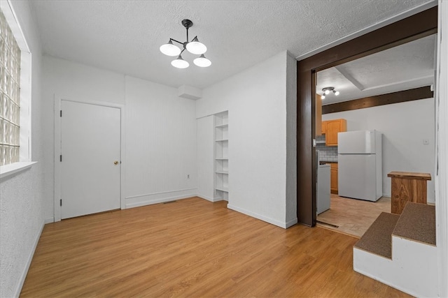 interior space with light hardwood / wood-style floors, an inviting chandelier, and a textured ceiling