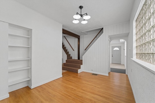 entrance foyer featuring hardwood / wood-style flooring, an inviting chandelier, and a textured ceiling