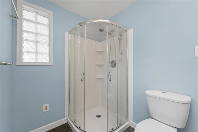 bathroom with hardwood / wood-style floors, walk in shower, and toilet