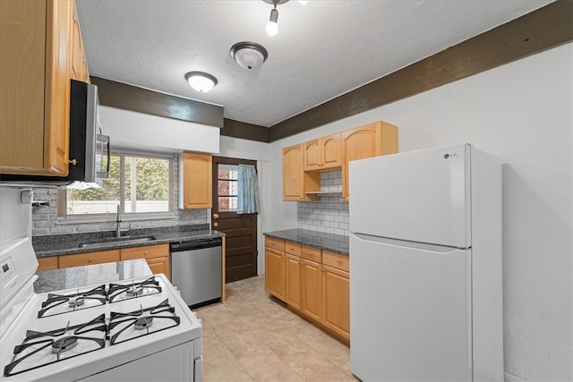 kitchen with dark stone counters, sink, decorative backsplash, appliances with stainless steel finishes, and light tile patterned floors