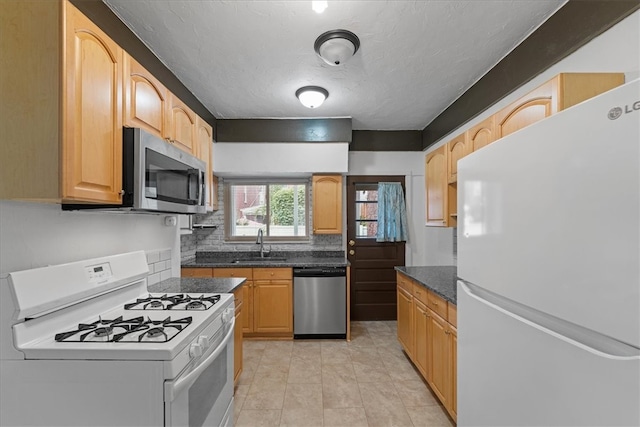 kitchen with tasteful backsplash, light brown cabinetry, sink, appliances with stainless steel finishes, and light tile patterned floors