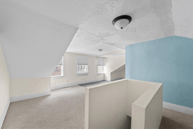 bonus room featuring light colored carpet, a textured ceiling, and vaulted ceiling