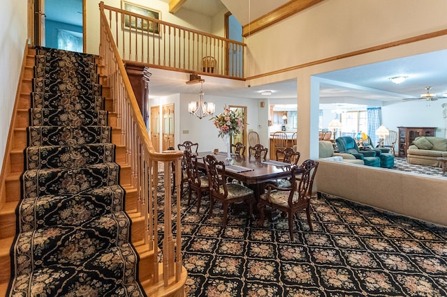 dining room featuring ceiling fan with notable chandelier, beamed ceiling, and a towering ceiling