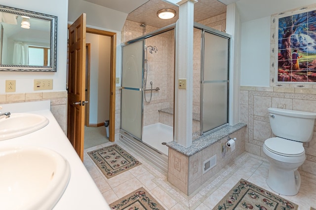 bathroom featuring tile patterned flooring, toilet, tile walls, a shower with shower door, and vanity