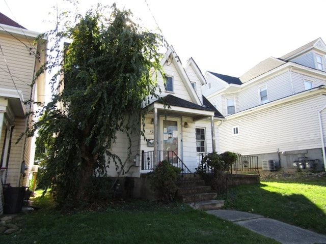 view of front of house with a front yard and central air condition unit