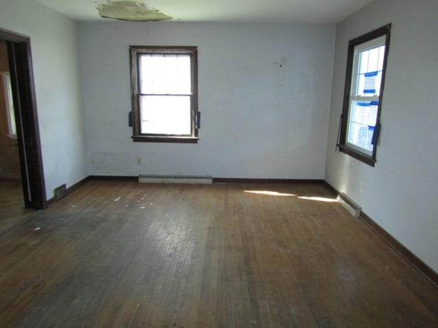 spare room featuring a baseboard heating unit and dark hardwood / wood-style floors