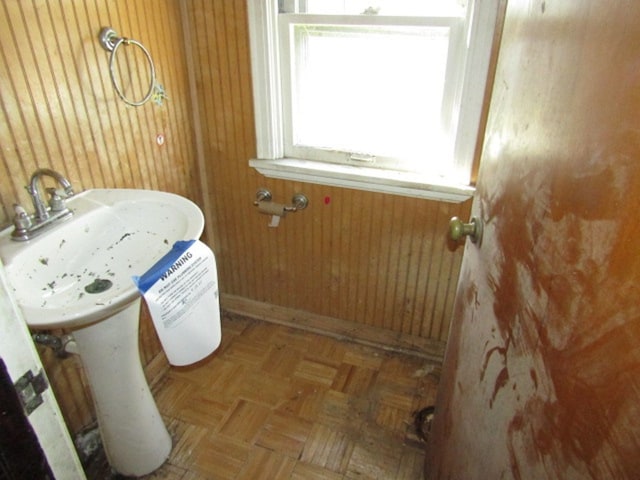 bathroom featuring parquet flooring and wooden walls